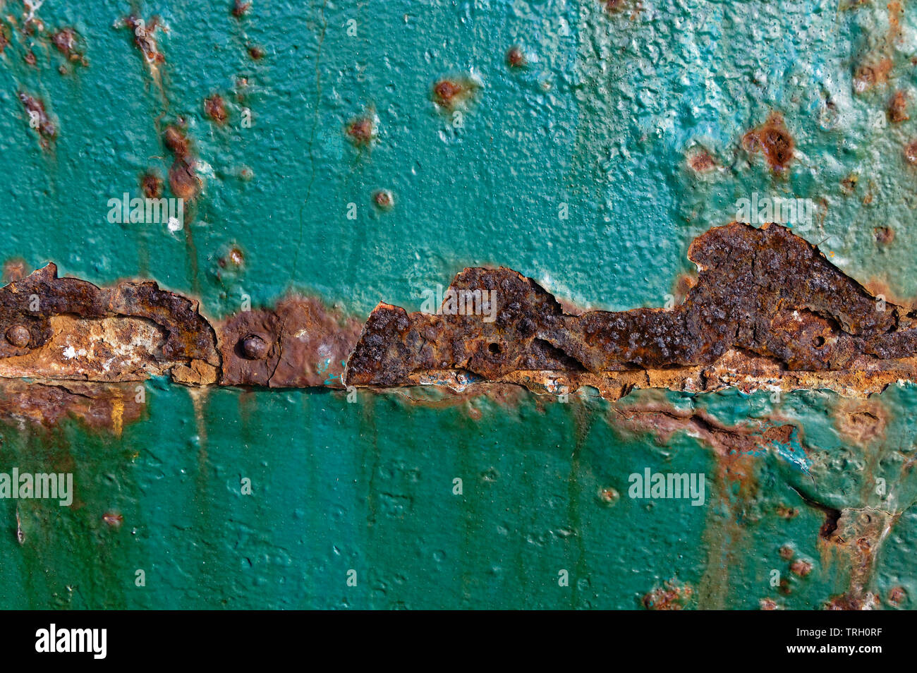Rust is eating away at the teal paint on a metal door Stock Photo