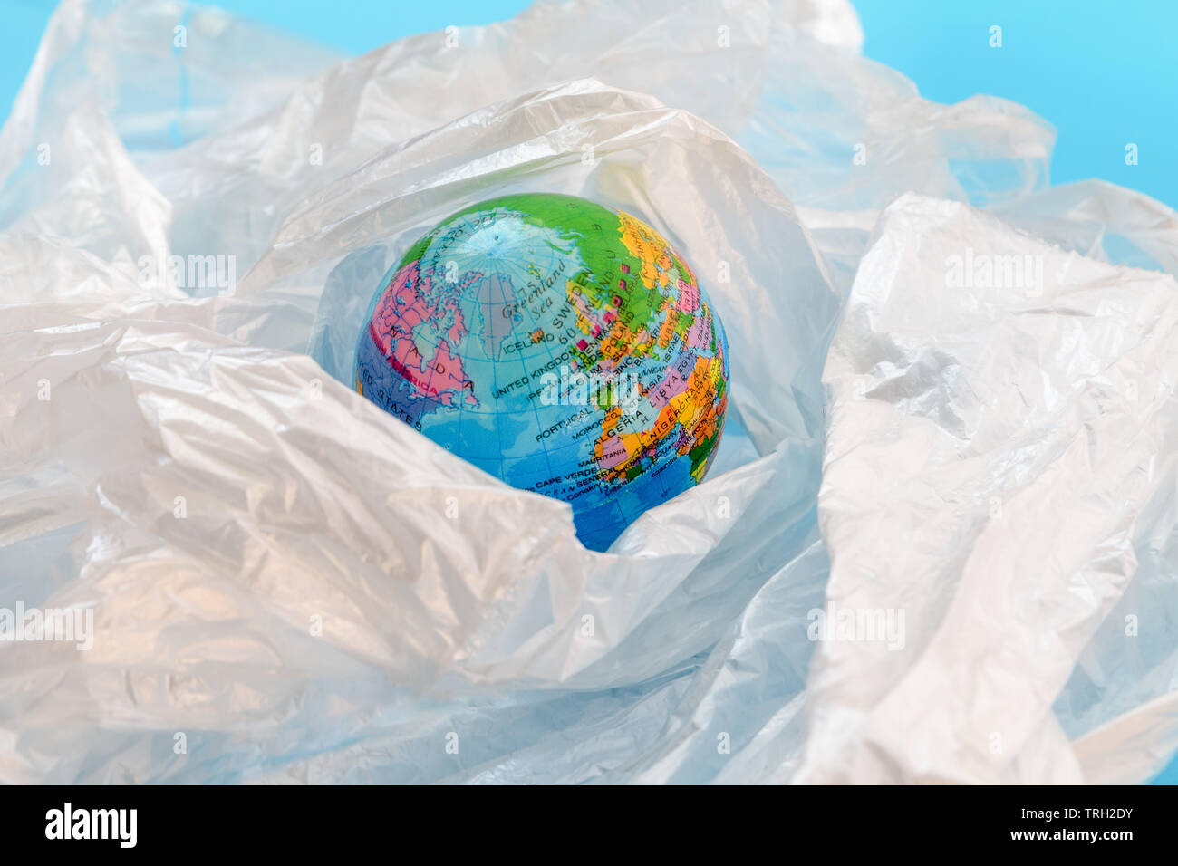 Concept of the plastic pollution problem in the world. The planet earth is floating around in a soup of white plastic bags on against blue background Stock Photo
