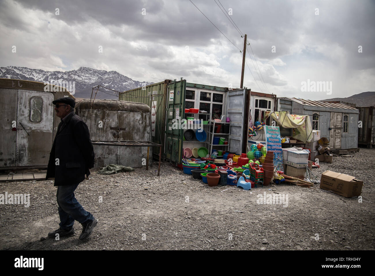 A local man passes by a stand selling plastic vessels in the Murghab container market, in Gorno-Badakhshan Autonomous Region, Tajikistan. Stock Photo