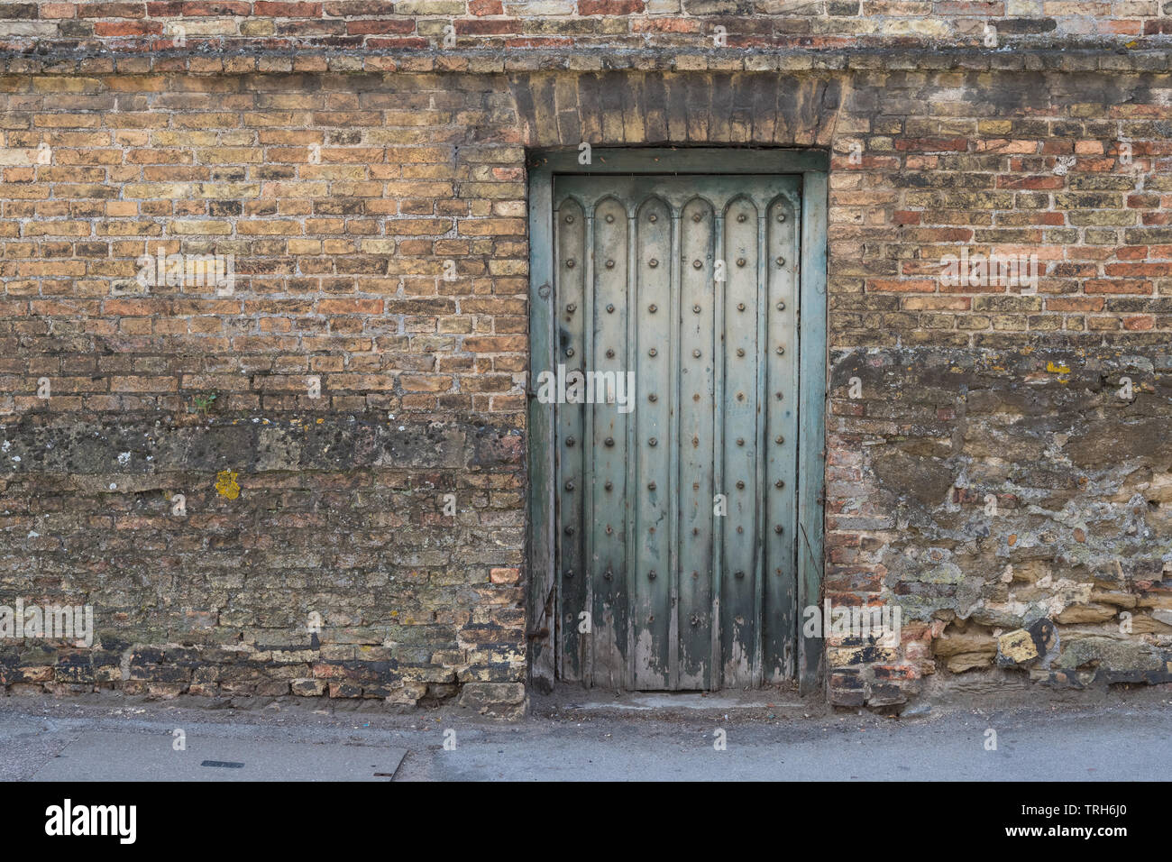 old faded turquoise weathered door in old brick wall, Newmarket, England, UK Stock Photo