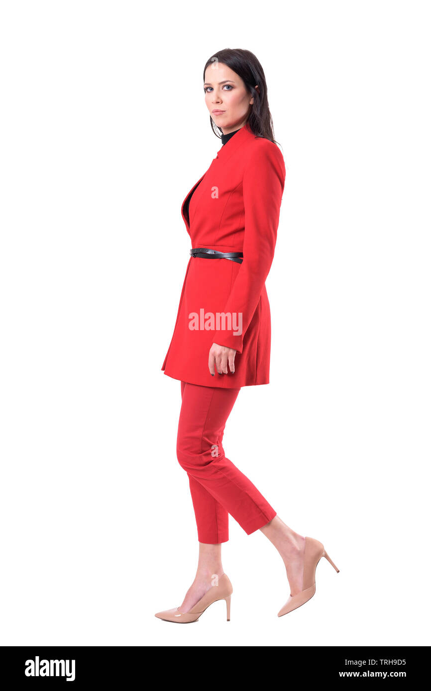 Confident successful serious business woman walking and looking at camera. Side view. Full body isolated on white background. Stock Photo