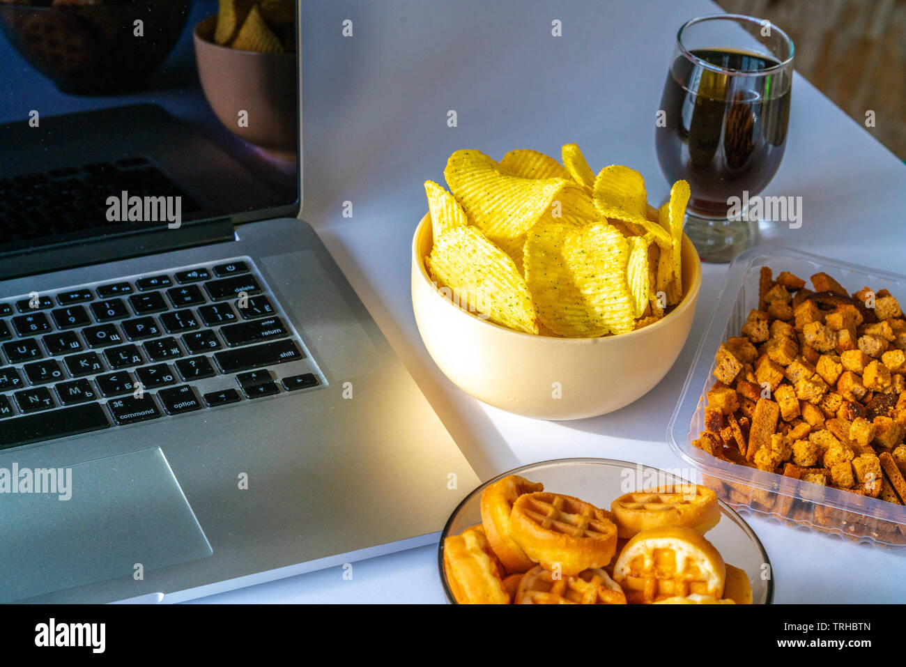 Bad habit. Work space with laptop, candies, chips, cola on white background. Junk food Stock