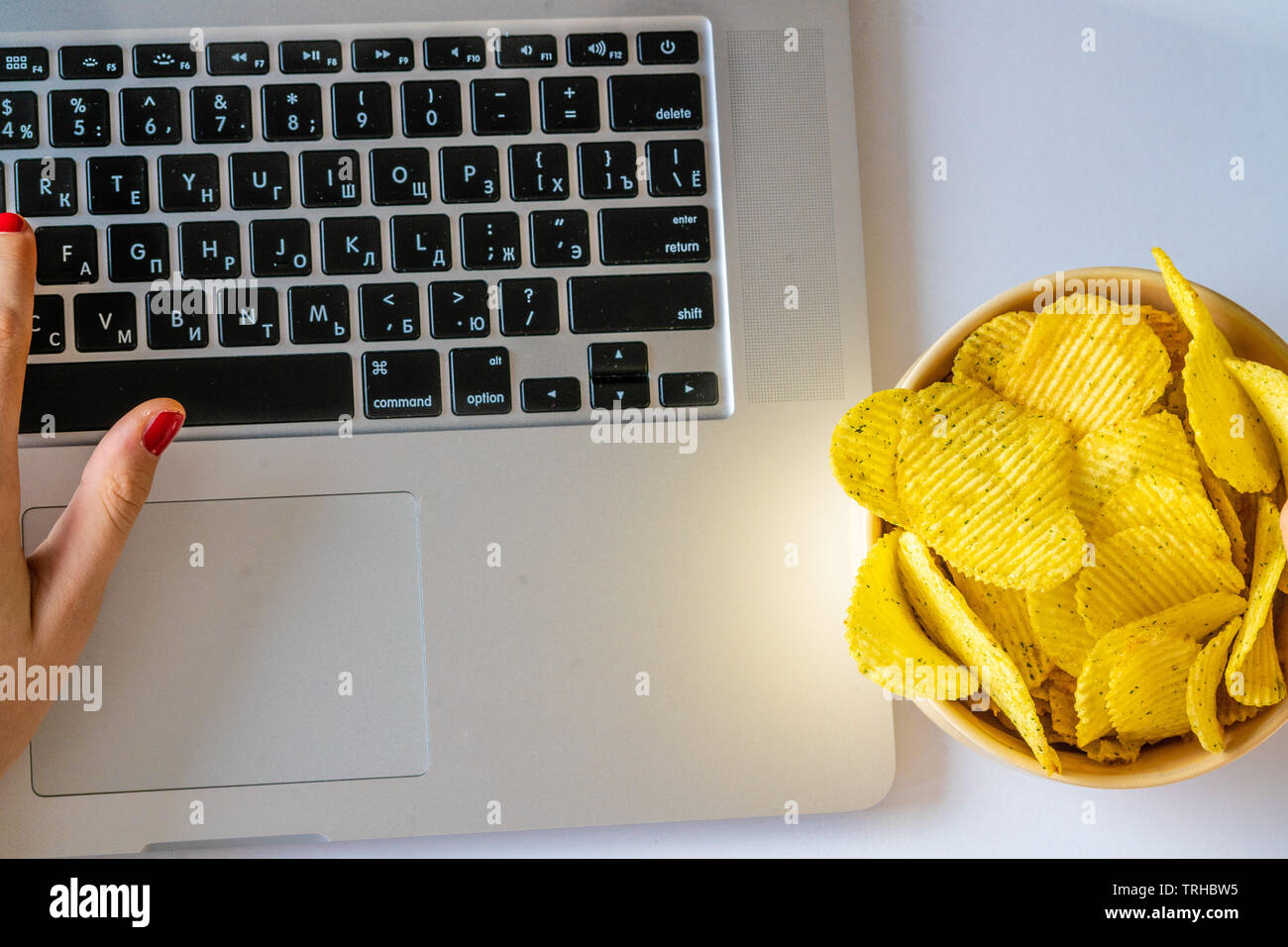 Bad habit. Work space with laptop, candies, chips, cola on white background. Junk food Stock