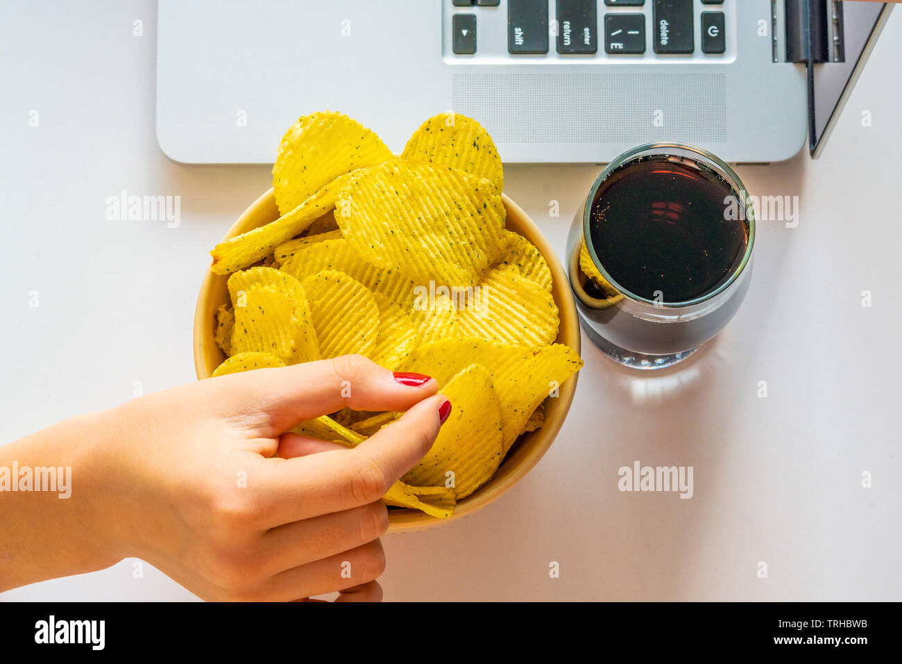 Bad habit. Work space with laptop, candies, chips, cola on white background. Junk food Stock