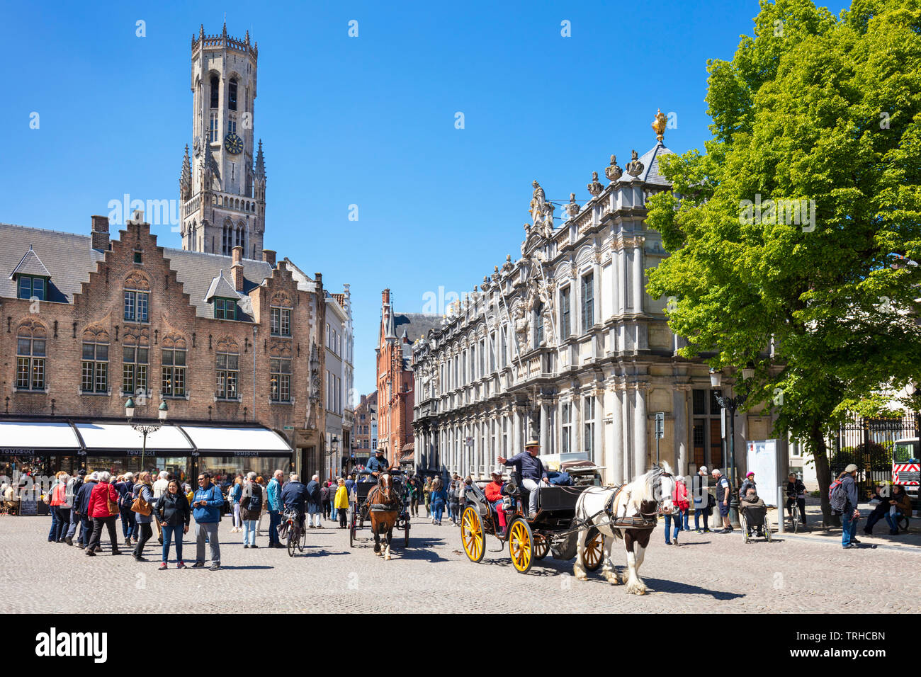 Belfry Bruges behind tourists in a horse and carriage riding around the old city of Bruges in Burg Square De Burg central Bruges Belgium EU Europe Stock Photo