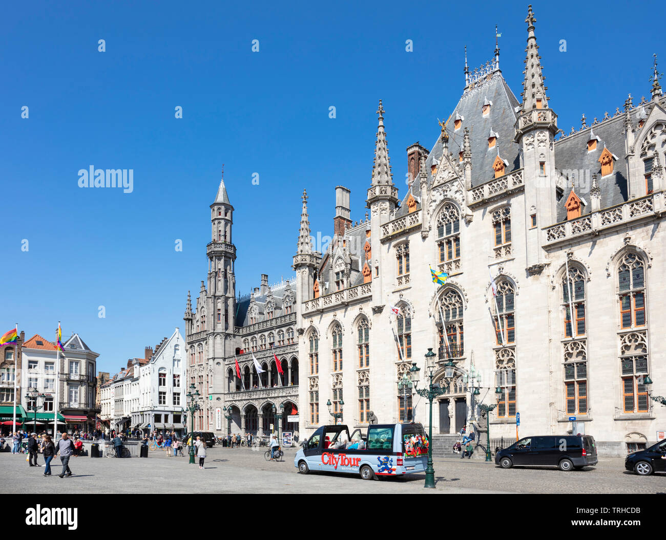 Tourists wandering around the historic market place going past the Provincial Court Provinciaal Hof in the Markt central Bruges Belgium EU Europe Stock Photo