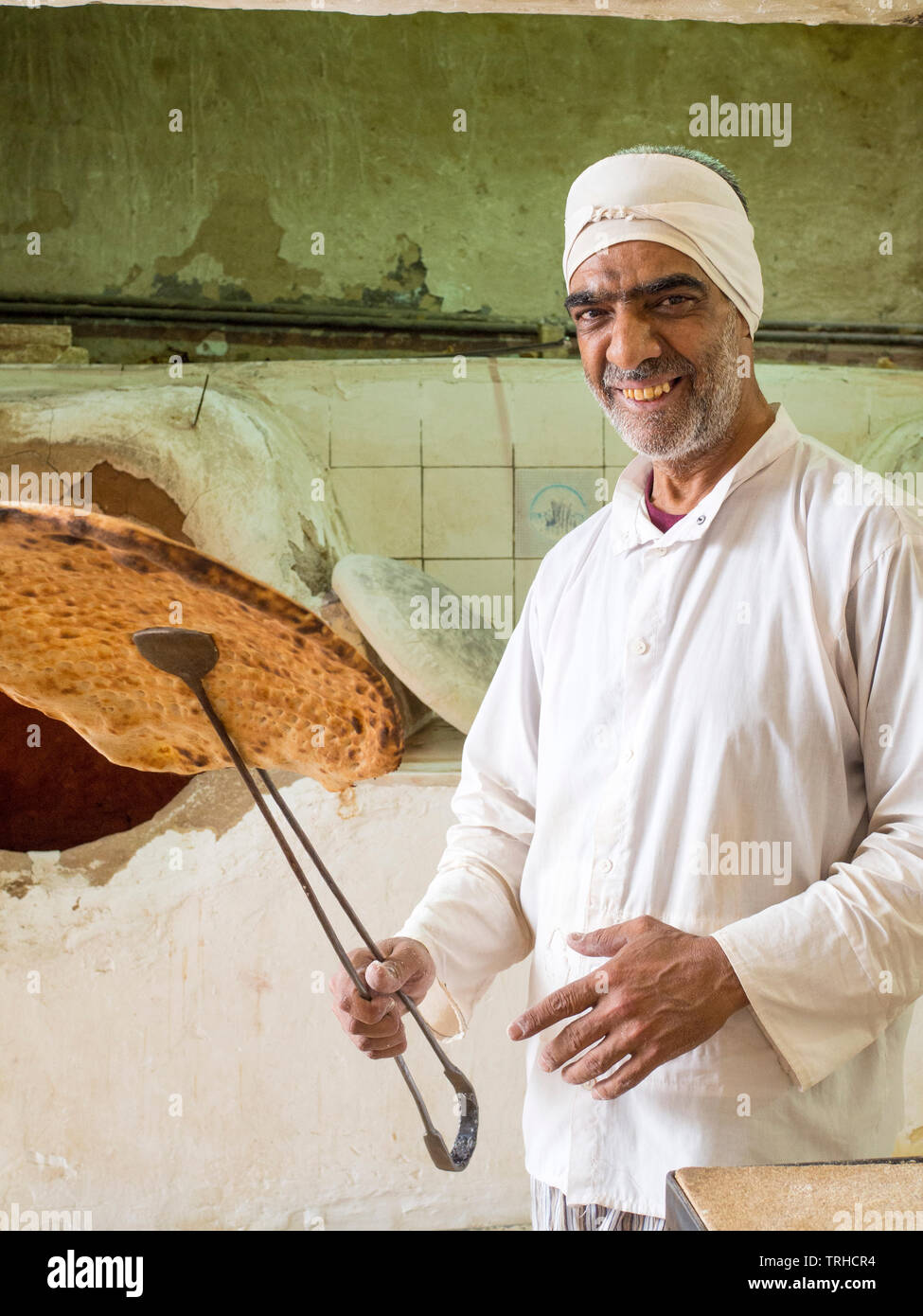 A man holds up naan bread baked in a traditional wood fired oven, known ...