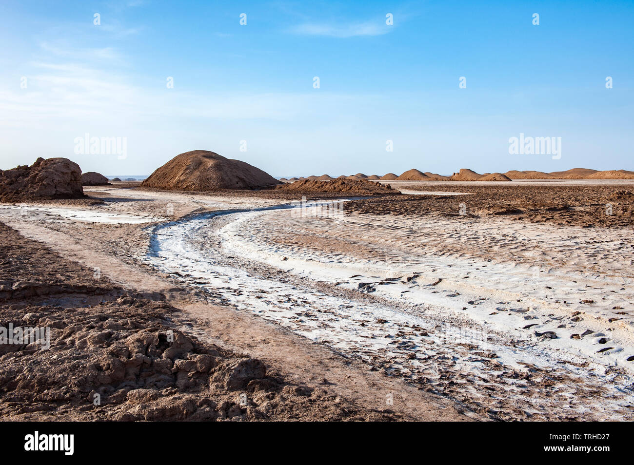 A salt crusted river with yardangs in the background in the Lut Desert in Shahad, Iran. Known as kaluts in Iran, yardangs are geological formations th Stock Photo