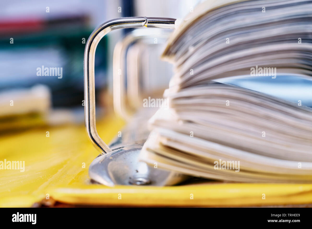 Open yellow binder close up , stack of white papers and bright metal rings , in the background office folders Stock Photo