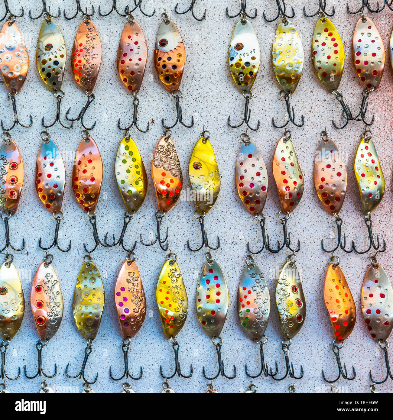 Countless of colorful fishing metal lures. Bait for fishing in the shape of a spoon with a hook on a gray background Stock Photo
