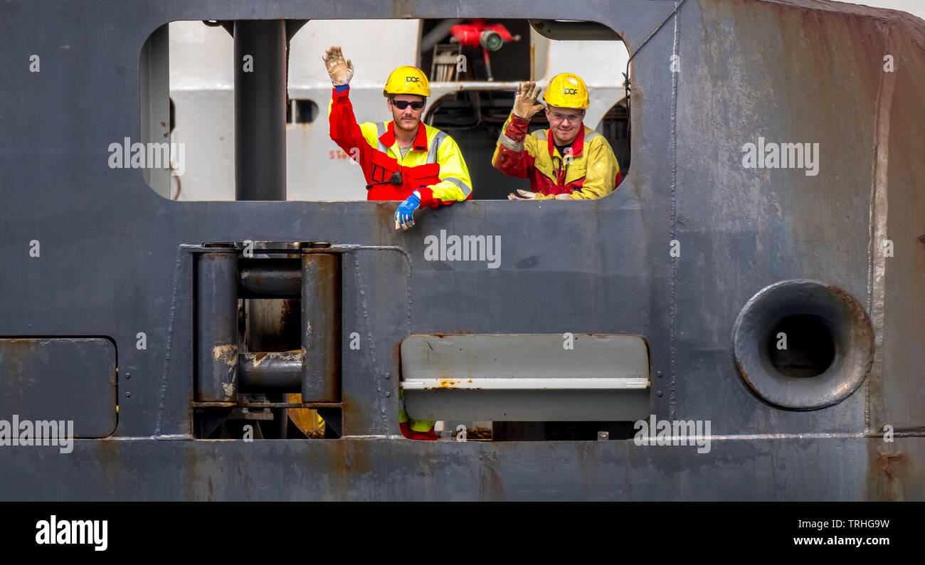 Waving norwegian sailors on an oil rig. Supply ship with safety helmet in Bergen, Hordaland, Norway, Scandinavia, Europe, Bergen, NOR, Travel, Tourism Stock Photo