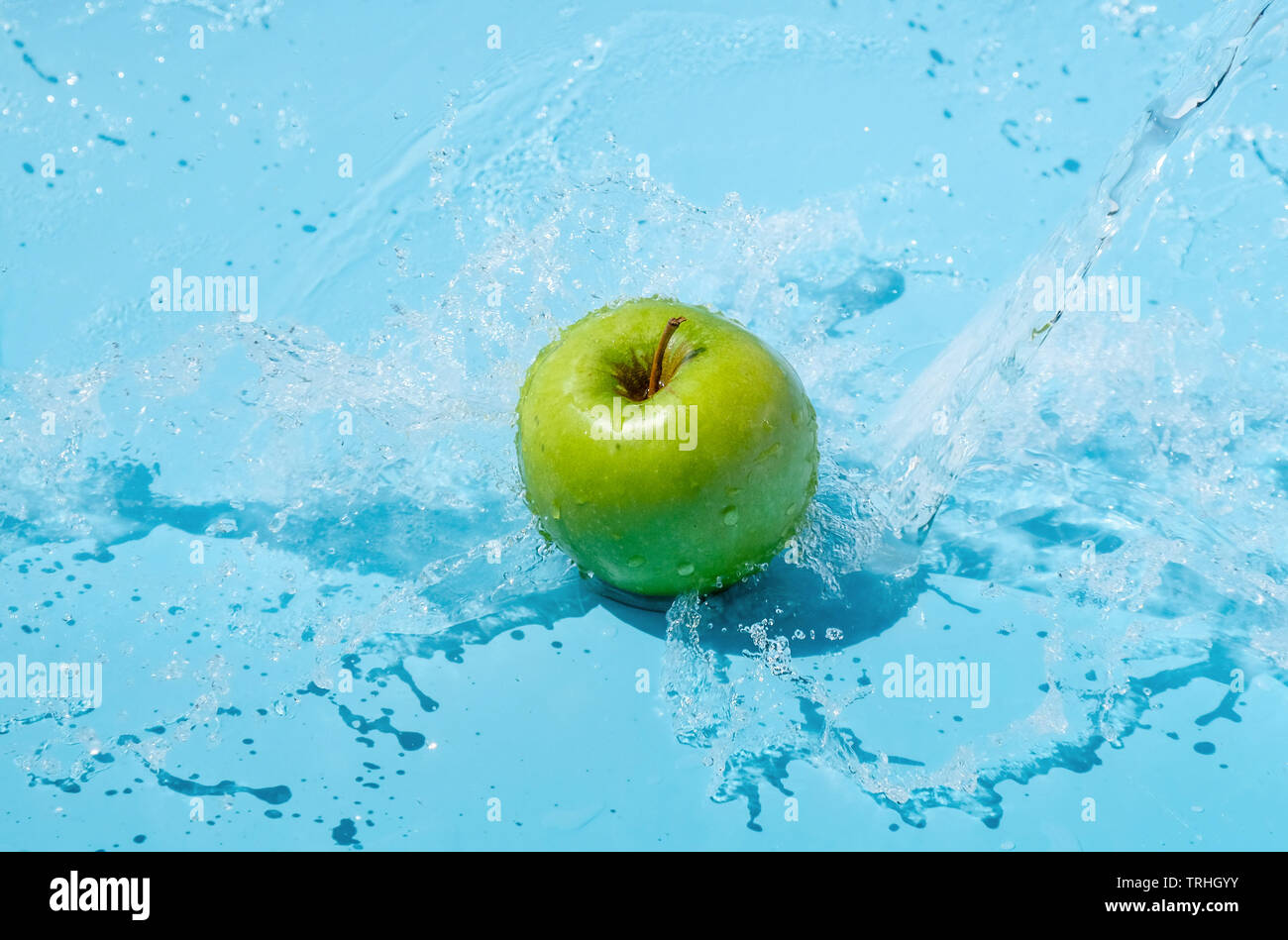 Green apple in water splash on blue background Stock Photo