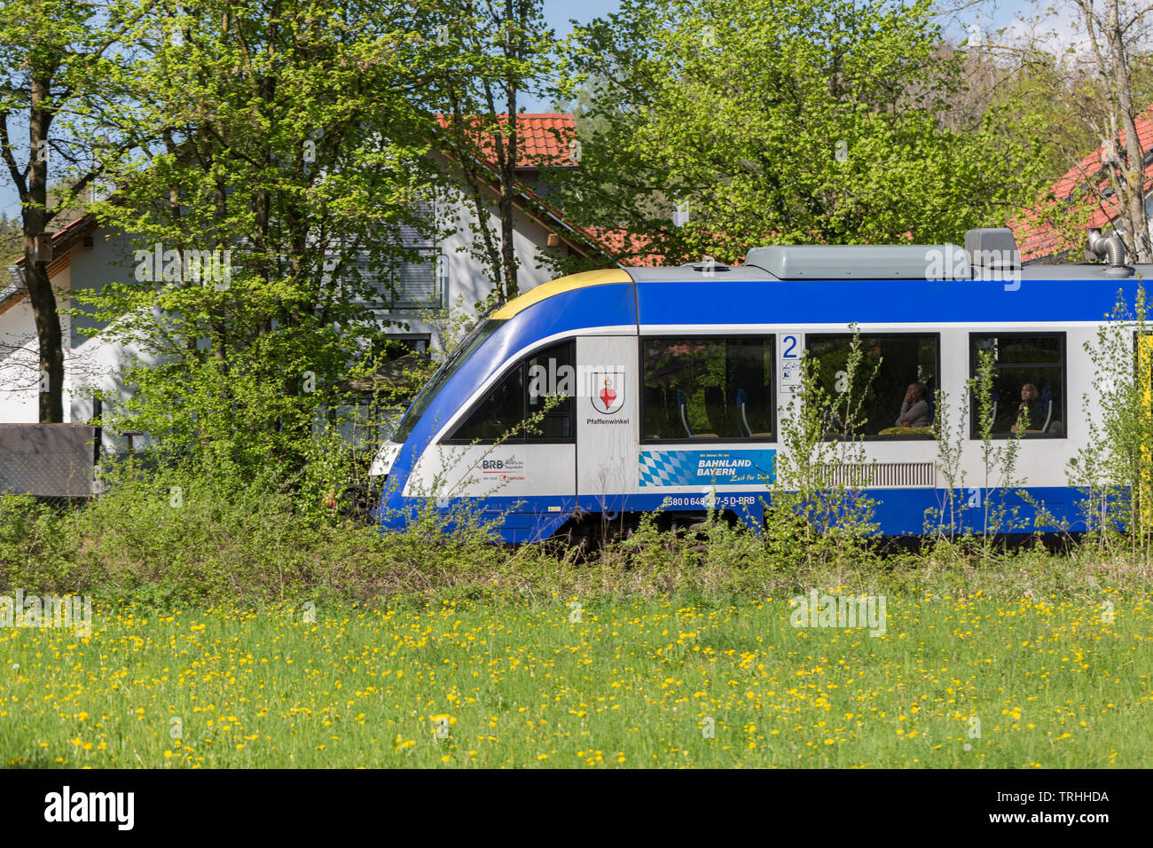 Train with the name 'Pfaffenwinkel' moving through the town of Utting. The train - a LINT 41 manufactured by Alstom - belongs to Bayerische Regiobahn. Stock Photo