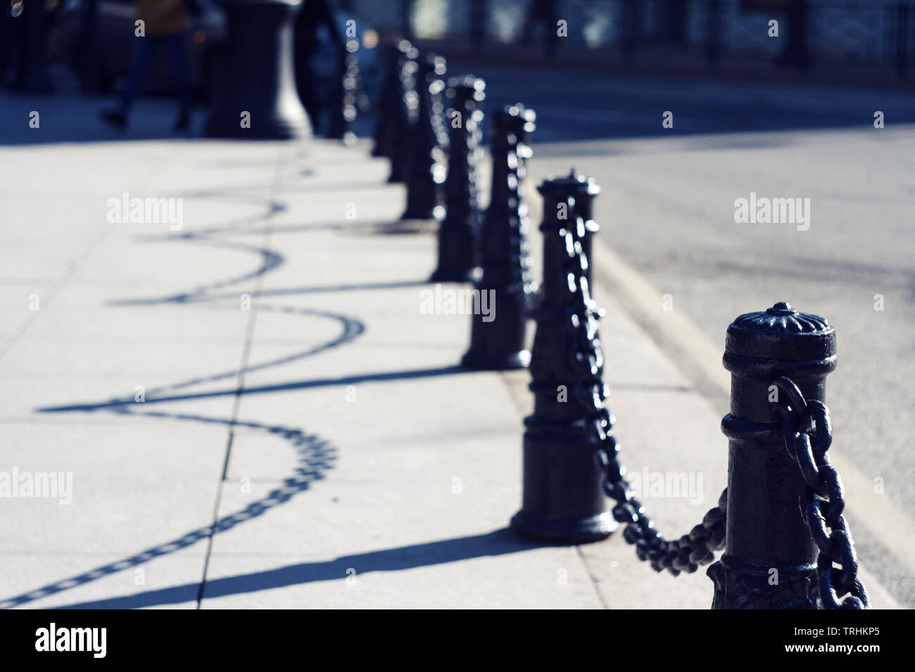 Beautiful graceful black decorative fence with chains that shines illuminated by sunlight and creates bokeh Stock Photo