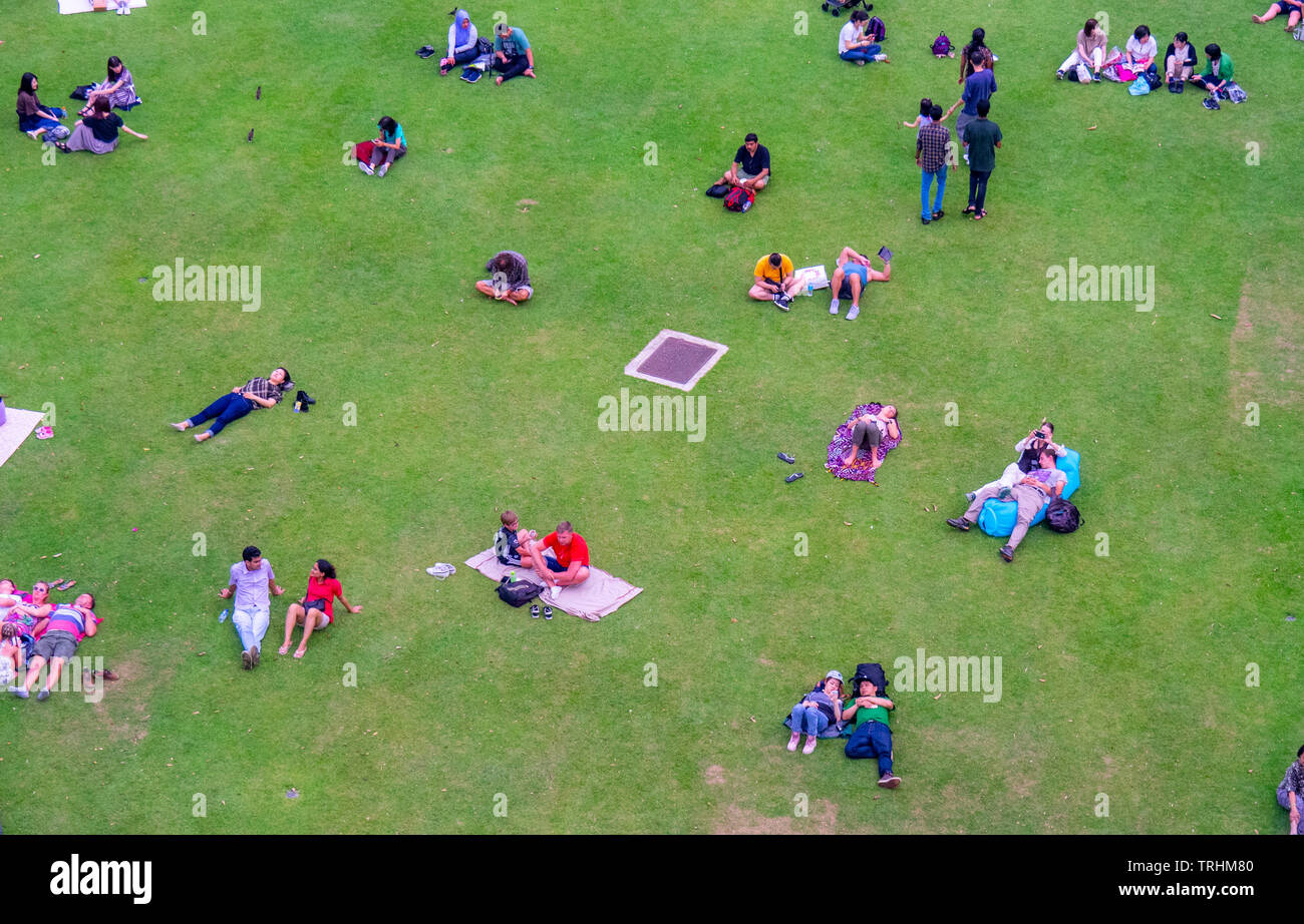 People families and couples sitting and lying down on the lawn resting at Gardens by the Bay Singapore. Stock Photo