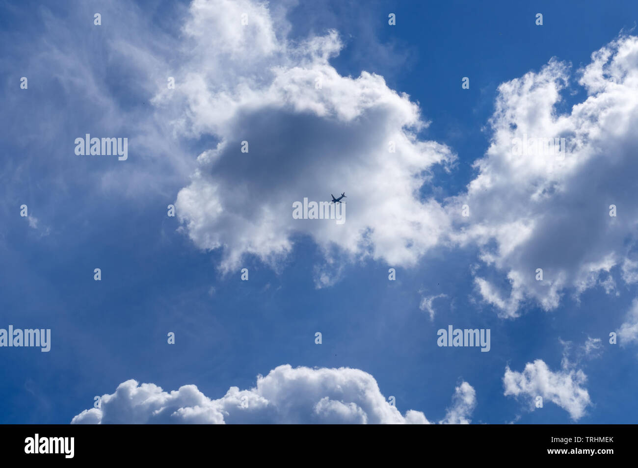 The plane flies against the blue sky with clouds Stock Photo - Alamy