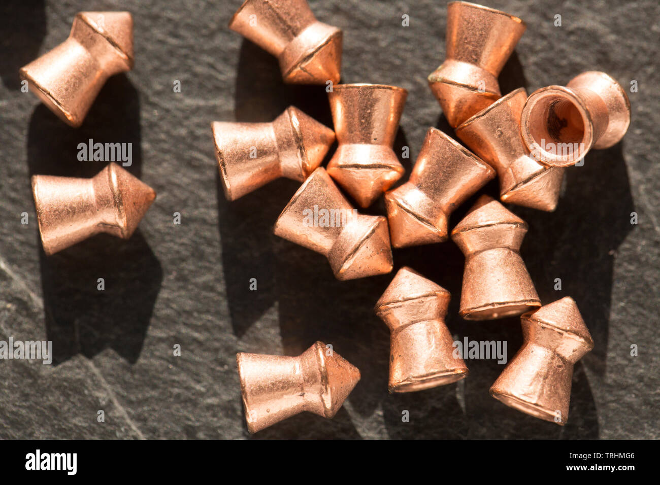 Copper-coated lead .22 calibre airgun pellets on a dark stone background that can be used in either air rifles or air pistols. England UK GB Stock Photo