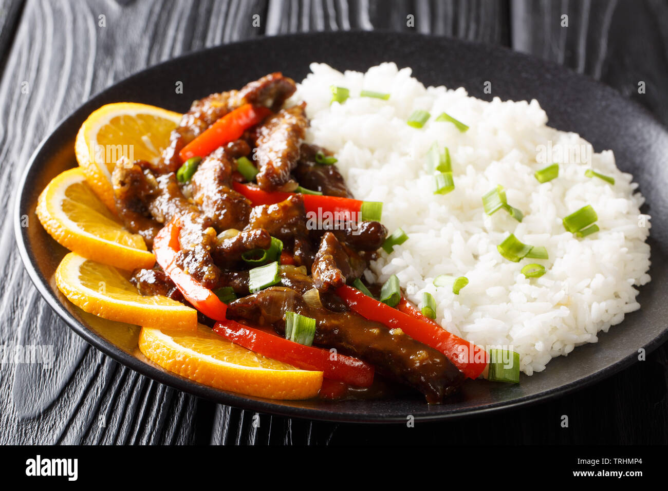 Fried Asian beef steak with sweet pepper in soybean orange sauce served with rice close-up on a plate on the table. horizontal Stock Photo
