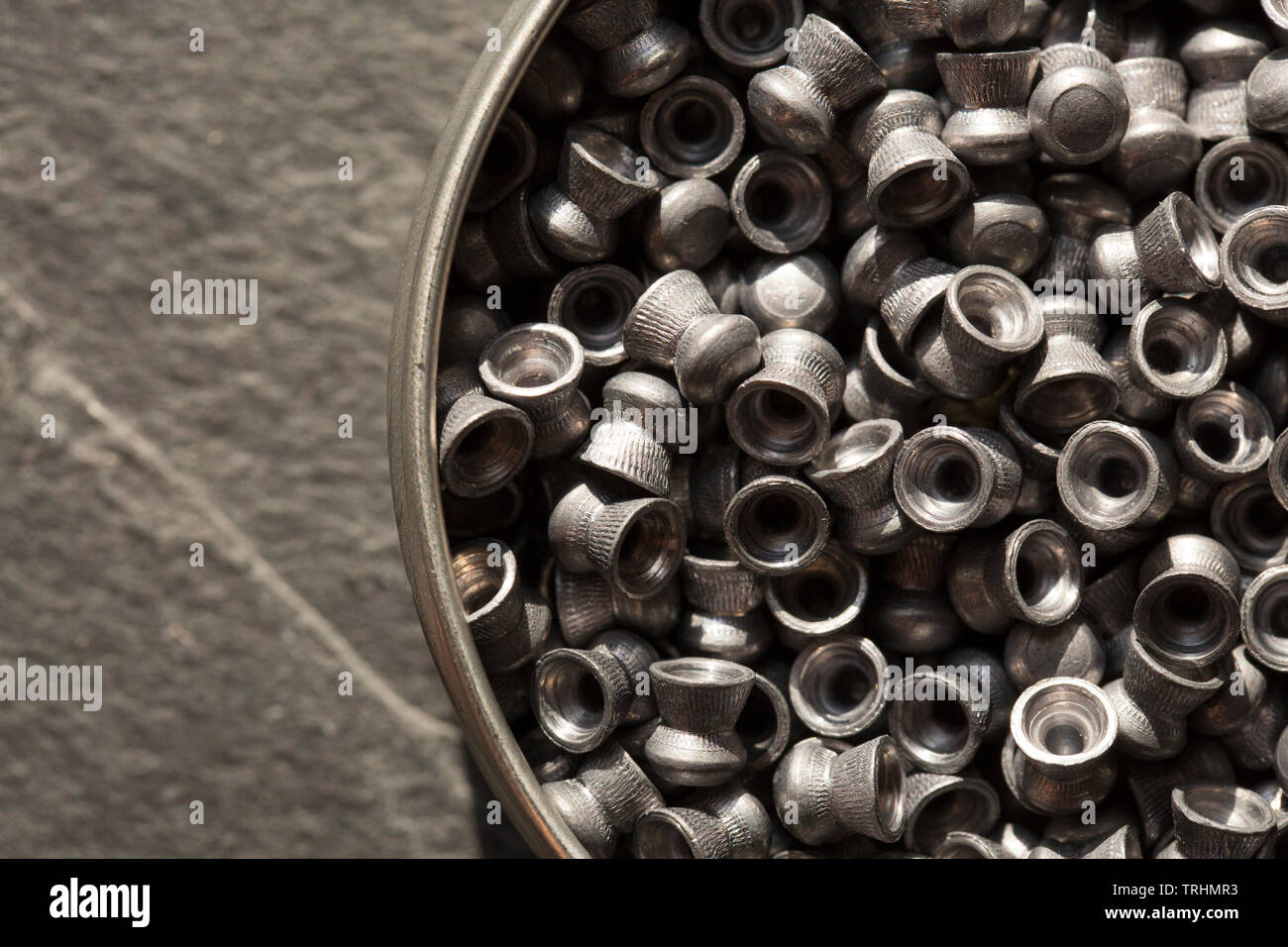 A tin of lead .22 calibre airgun pellets on a dark stone background that can be used in either air rifles or air pistols. England UK GB Stock Photo