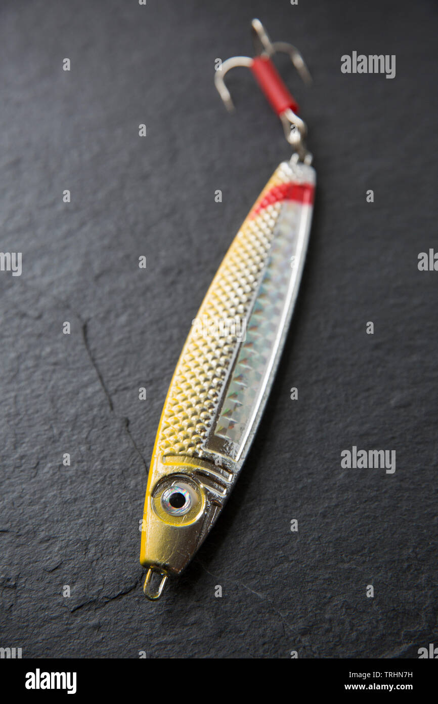 A metal Fladen fishing lure equipped with a treble hook. Lures such as these are used normally for sea fishing from a boat when drifting over wrecks a Stock Photo