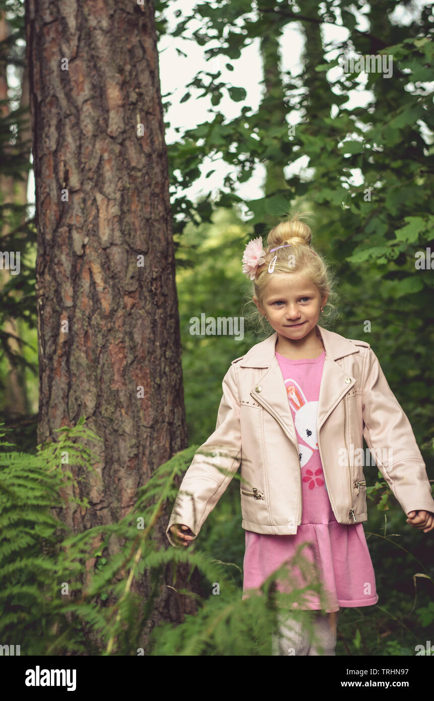 lovely blond little girl and green trees Stock Photo