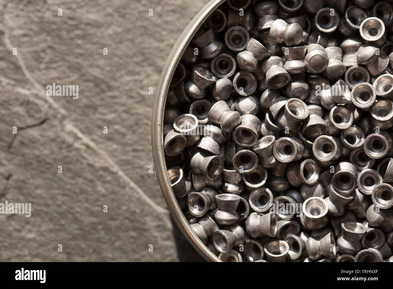 A tin of lead .22 calibre airgun pellets on a dark stone background that can be used in either air rifles or air pistols. England UK GB Stock Photo