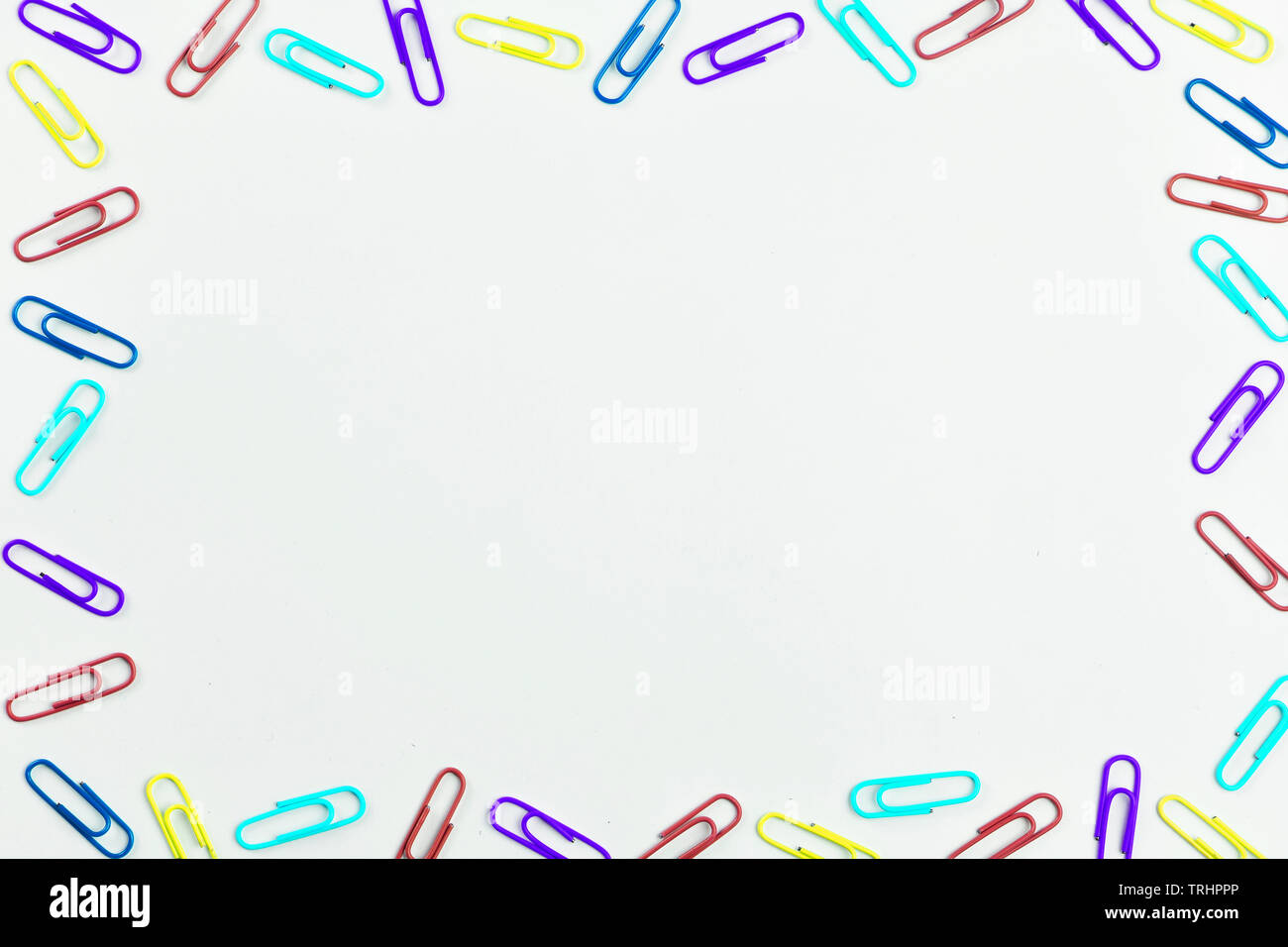 Multicolored paper clips on white background with space for text. Stock Photo