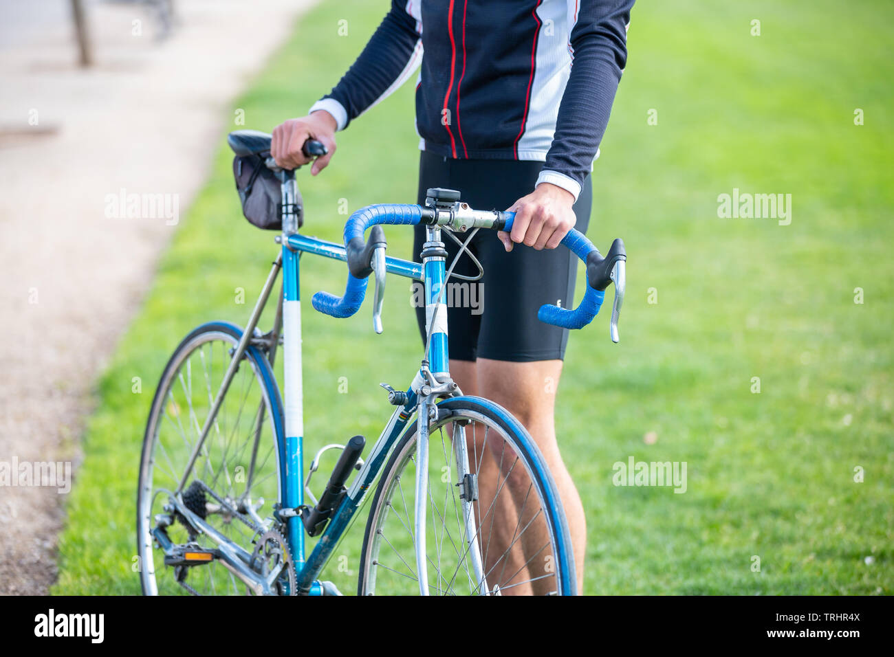 Unrecognizable young fit male cyclist in sportswear sitting on bike in park Stock Photo