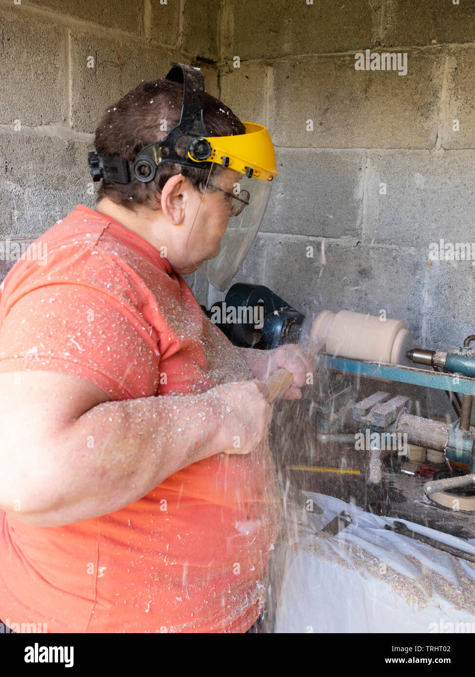 Mature, 65 year old, female crafter turning a wooden vase on her lathe Stock Photo