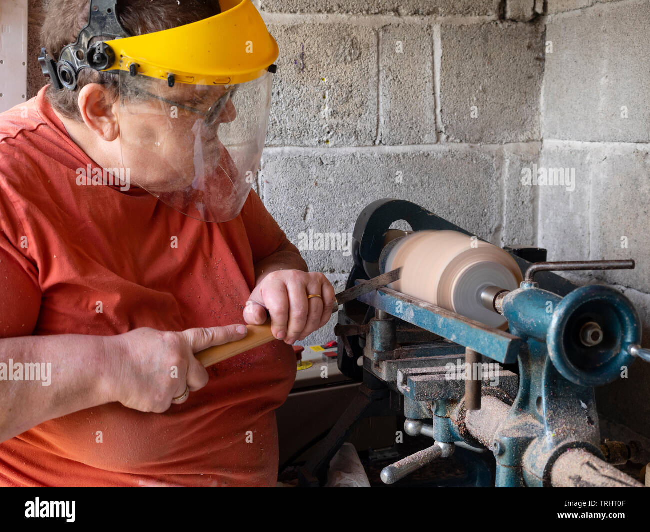 Mature, 65 year old, female crafter turning a wooden vase on her lathe Stock Photo