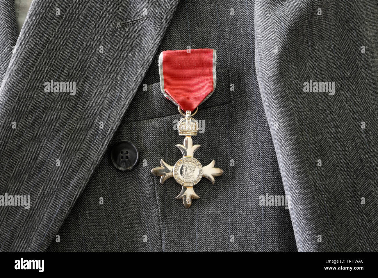 British MBE medal worn on grey suit, Member of the British Empire award life event honours system Stock Photo