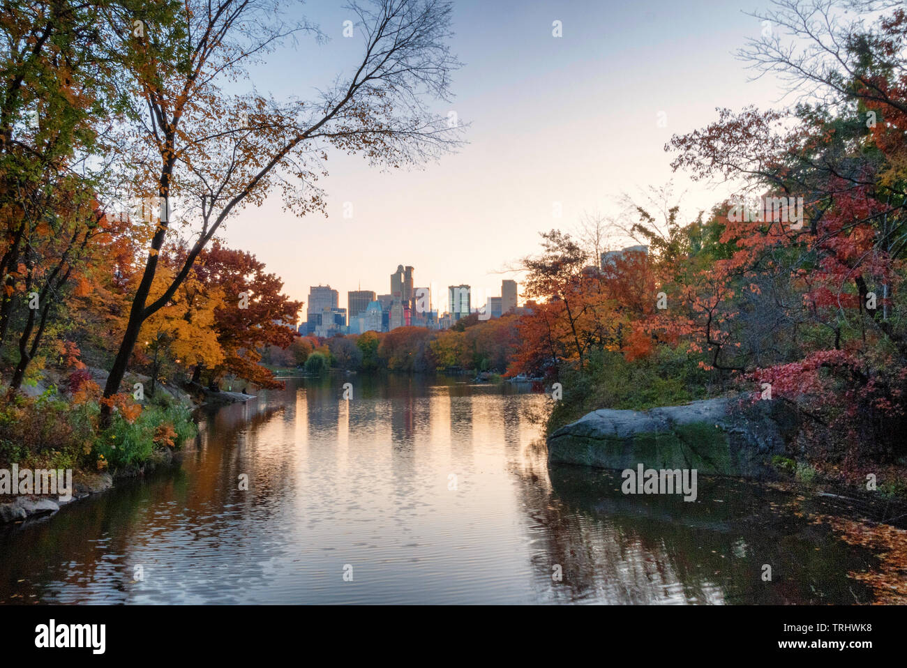 Sunset at Central Park on a cool autumn day with colorful leaves and skyscrapers in the background Stock Photo