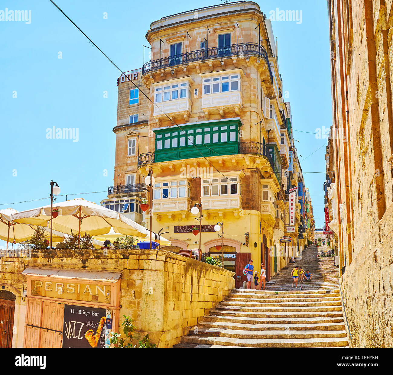 VALLETTA, MALTA - JUNE 19, 2018: The narrow hilly St Ursula street with long staircase, historic edifices, outdoor restaurants and small shops, on Jun Stock Photo