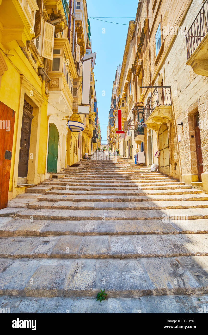 The long and narrow St John street with a staircase stretches up the hill to the city center of Valletta, Malta. Stock Photo