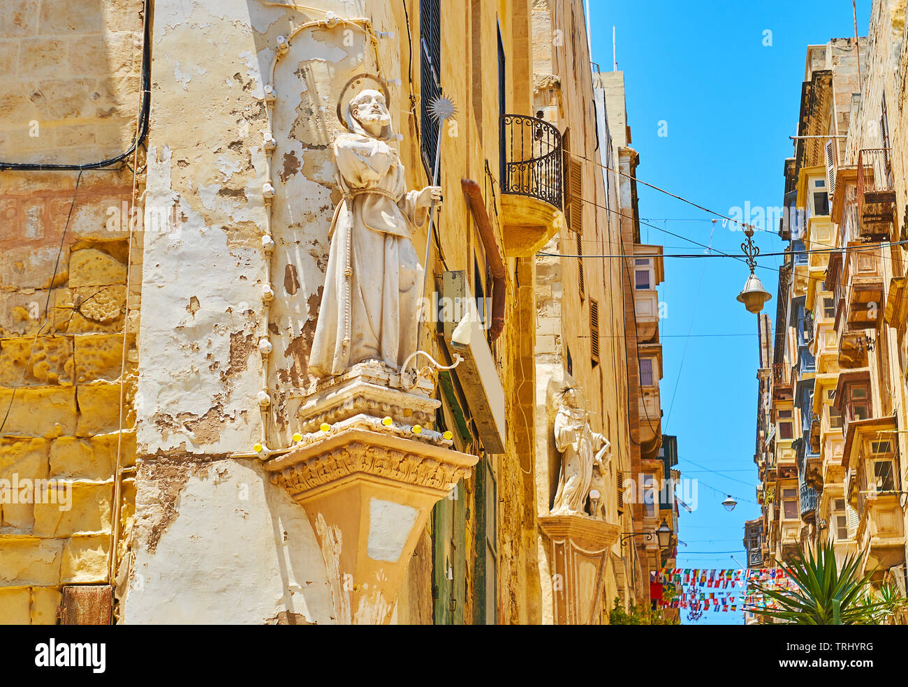The corner wall statues of St Francis of Paola and St Francis of Assisi (on background) are the notable landmarks of St Lucia street, Valletta, Malta. Stock Photo