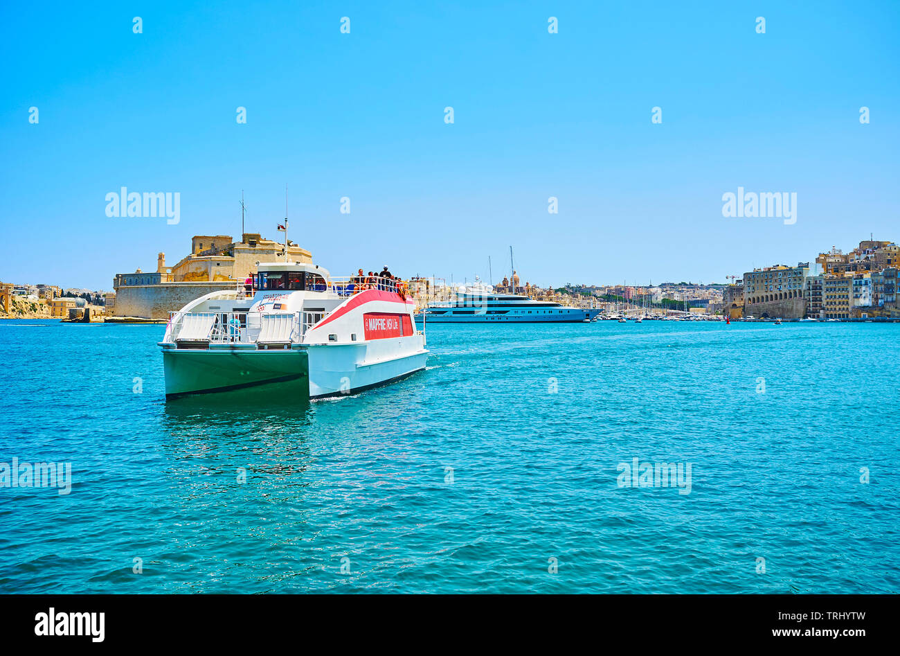 VALLETTA, MALTA - JUNE 19, 2018: The passenger ferry floats from Birgu to Valletta across the Grand Harbour with a view on Fort St Angelo on the backg Stock Photo