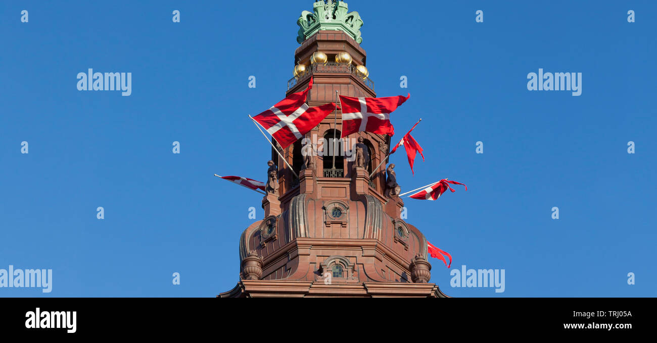 The Dannebrog, national flag of Denmark, in tower openings of Christiansborg Castle, parliament building in Copenhagen, Denmark, on special occasions Stock Photo