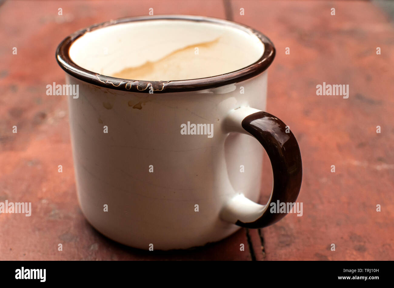 Metal enamel mug with remains of coffee drink on old table of painted