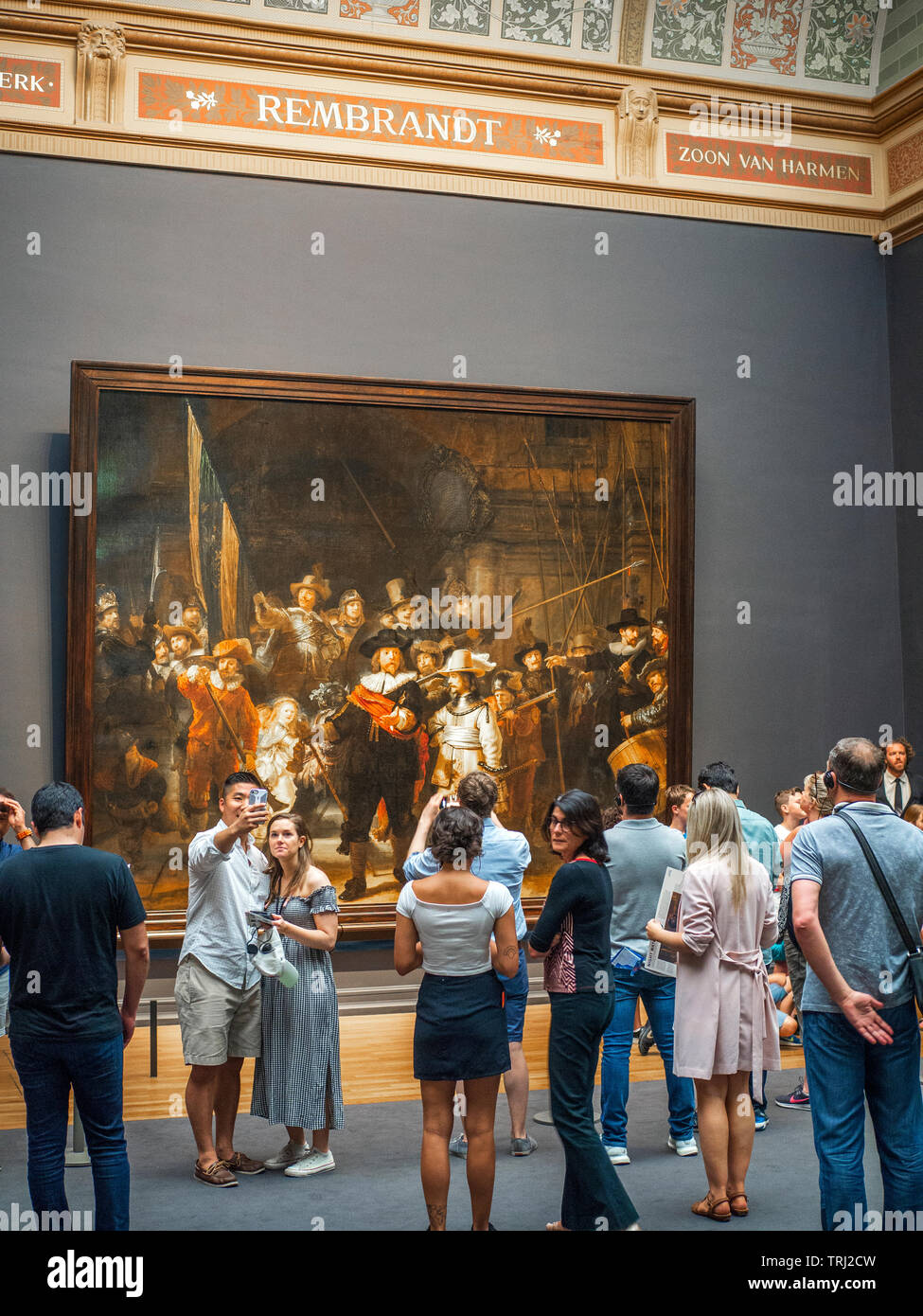 Tourist observing The Night Watch, a painting by Rembrandt Harmenszoon van Rijn, at the Rijksmuseum in Amsterdam, The Netherlands. Rembrandt is consid Stock Photo