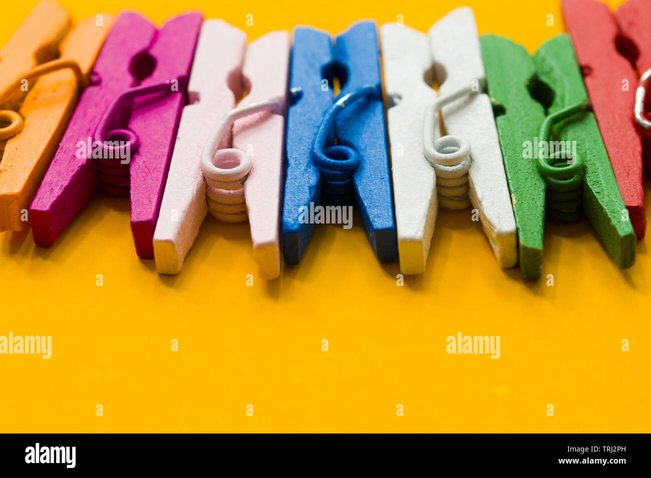 colored clothespins on a yellow background Stock Photo