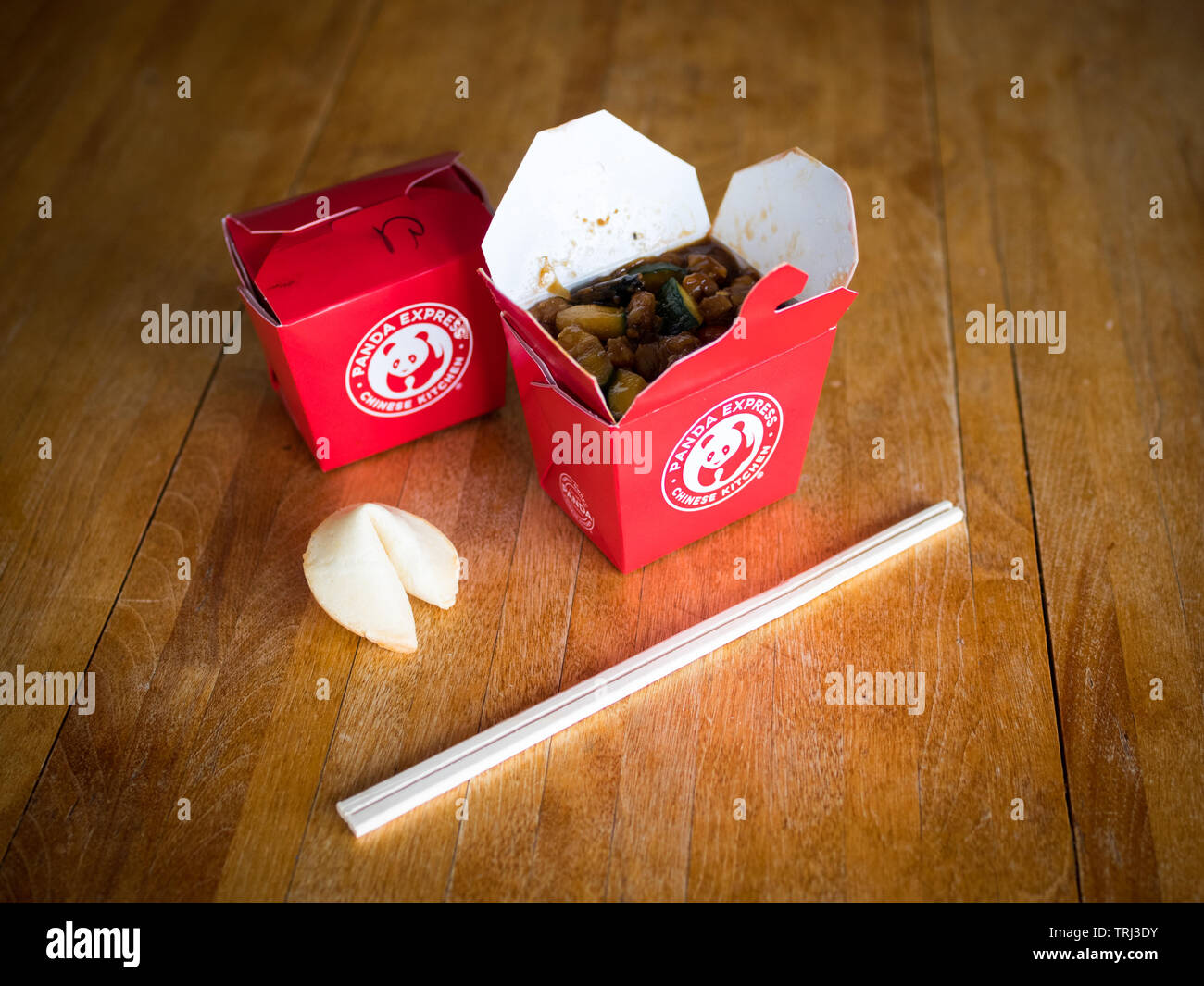 Takeout boxes of kung pao chicken from Panda Express restaurant, a fortune cookie, and chopstocks. Stock Photo