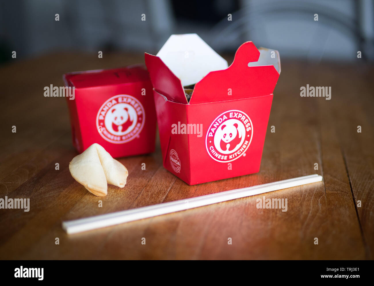 Takeout boxes of kung pao chicken from Panda Express restaurant, a fortune cookie, and chopstocks. Stock Photo