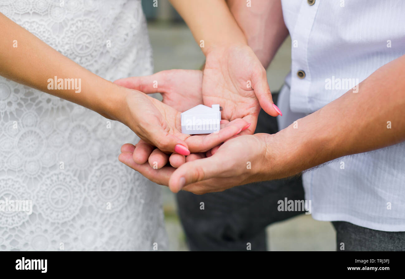 A man and a woman holding in their hands a small house. Close up. Horizontal photography Stock Photo