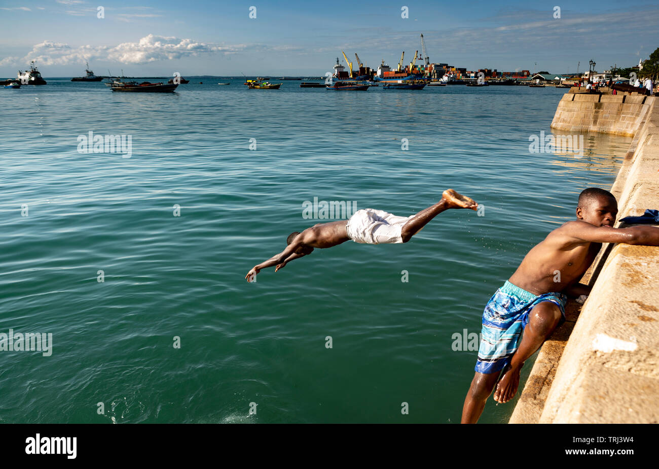 Teenage boys swimming and diving off the concrete seawall into the