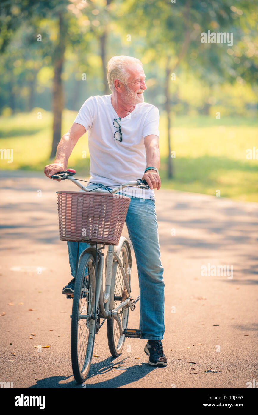 Old man riding bike hi-res stock photography and images - OlD Man RiDing On Bicycle In GarDen At Sunset Healthcare Concept Relaxing In Park TRJ3YG