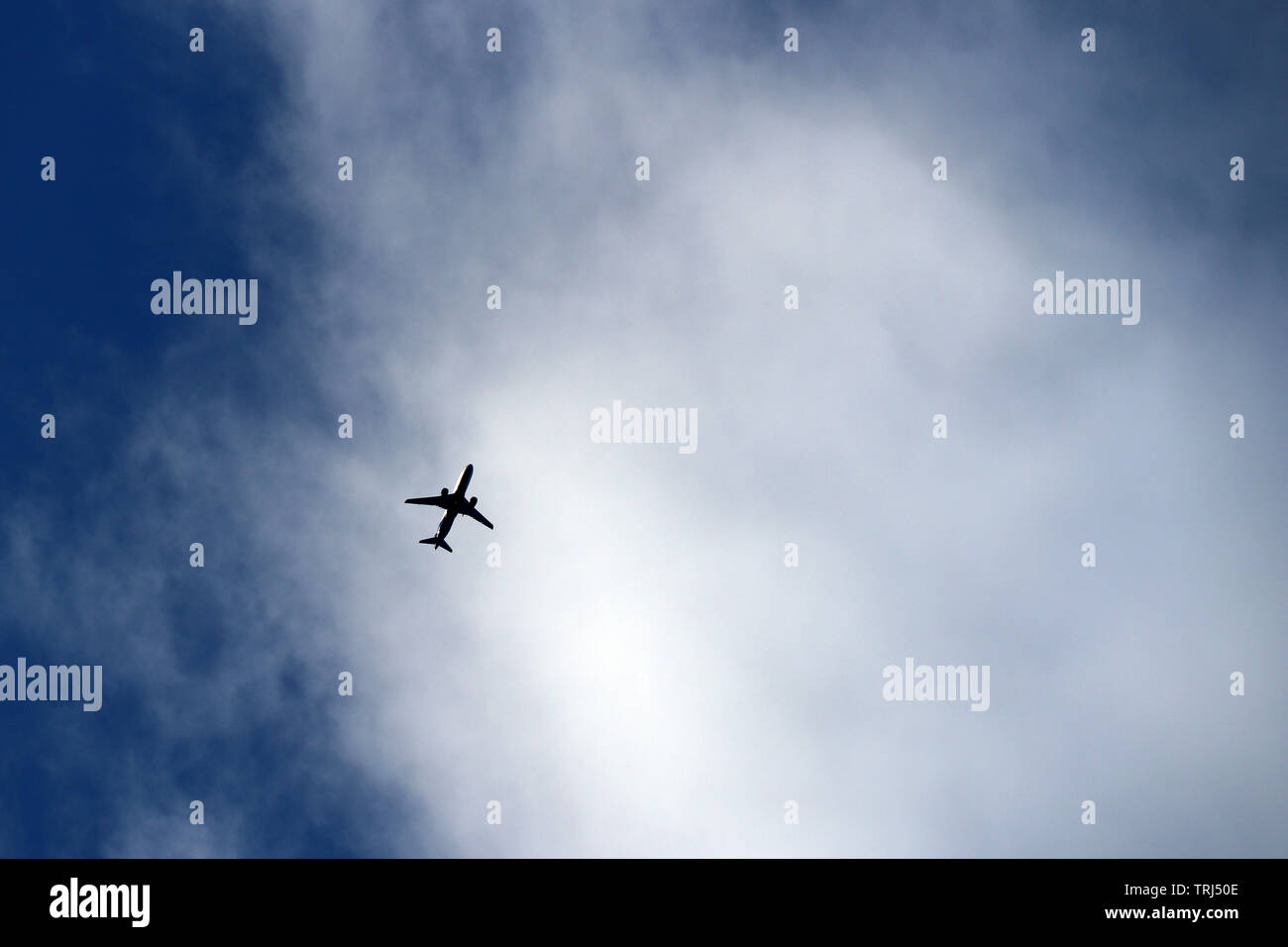 Airplane flying in the sky on background of clouds. Silhouette of a commercial plane, turbulence concept Stock Photo