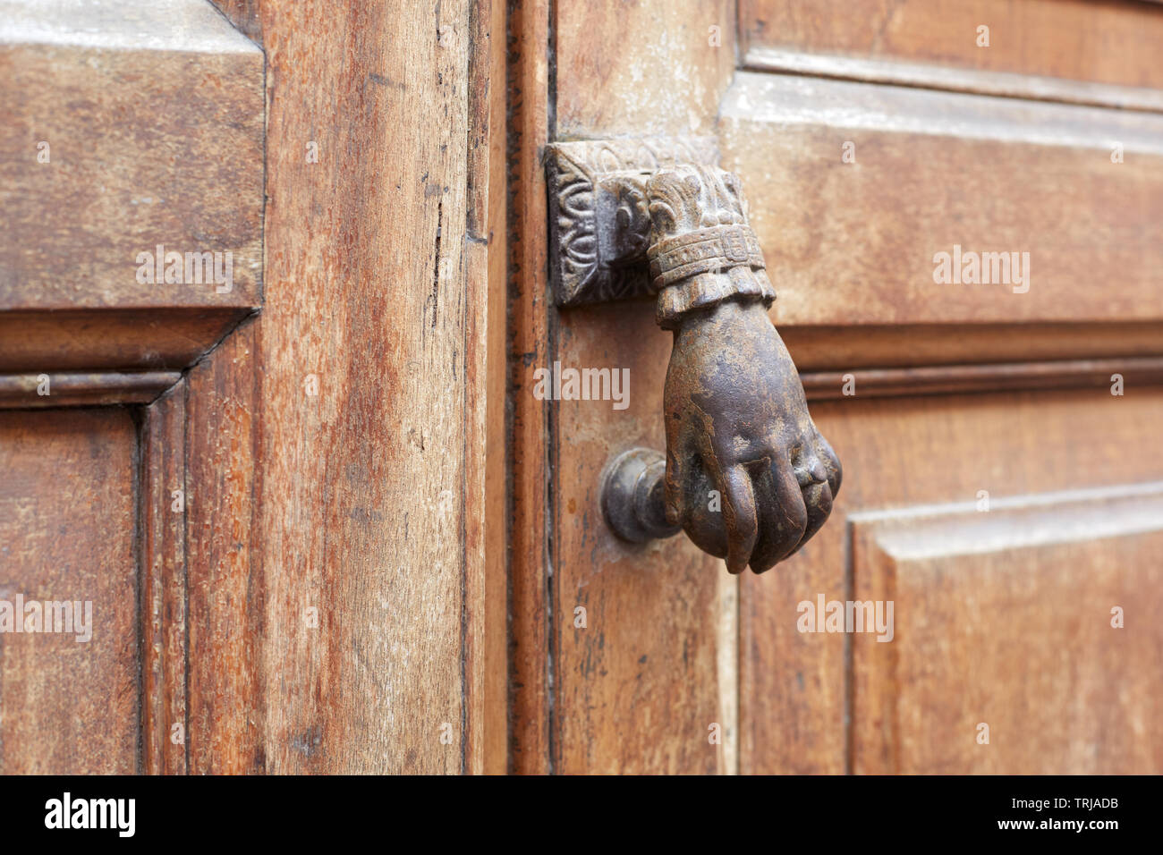 Old door knocker in shape of hand and wooden door background Stock Photo