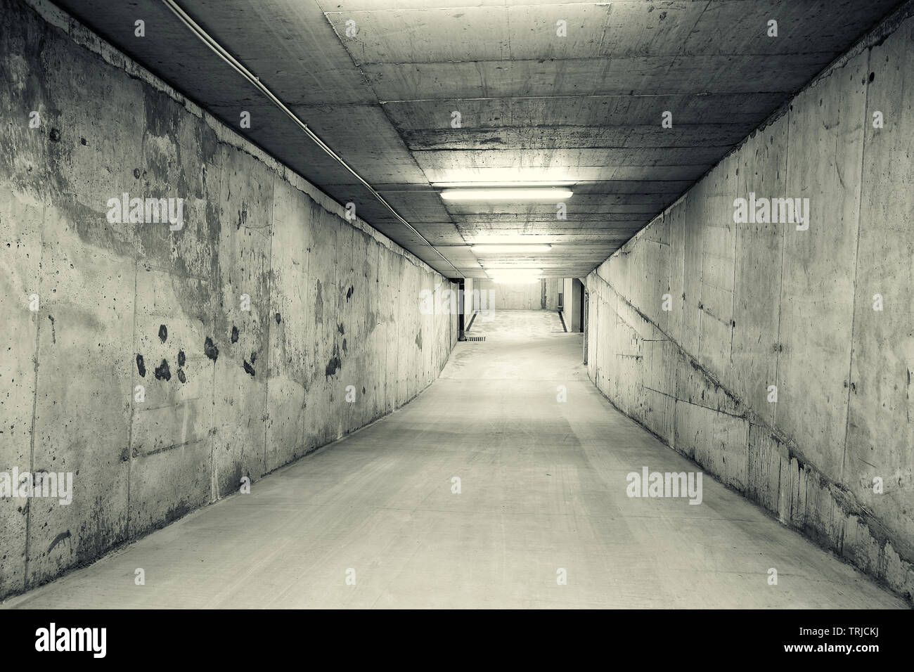 Empty, tunnel like downhill ramp of an underground car parking. Black and white image Stock Photo