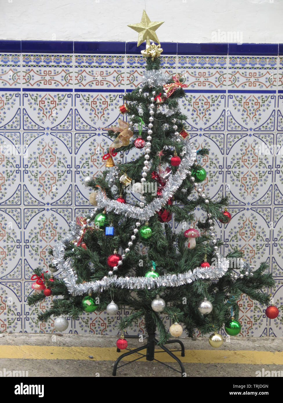 Small Decorated Artificial Christmas Tree On Pavement Against