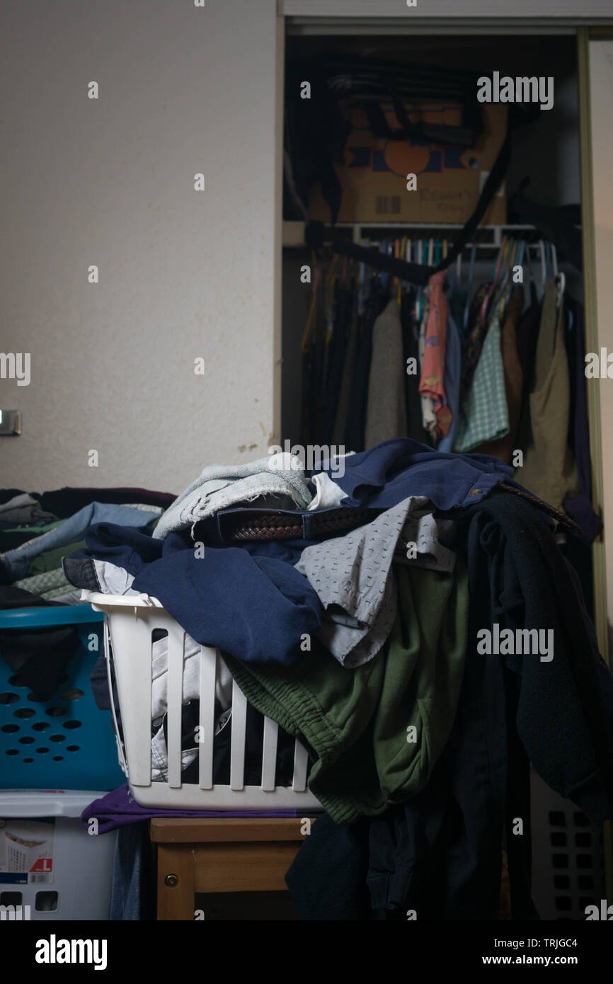 stacks of clothes and laundry with a closet full of clothes Stock Photo